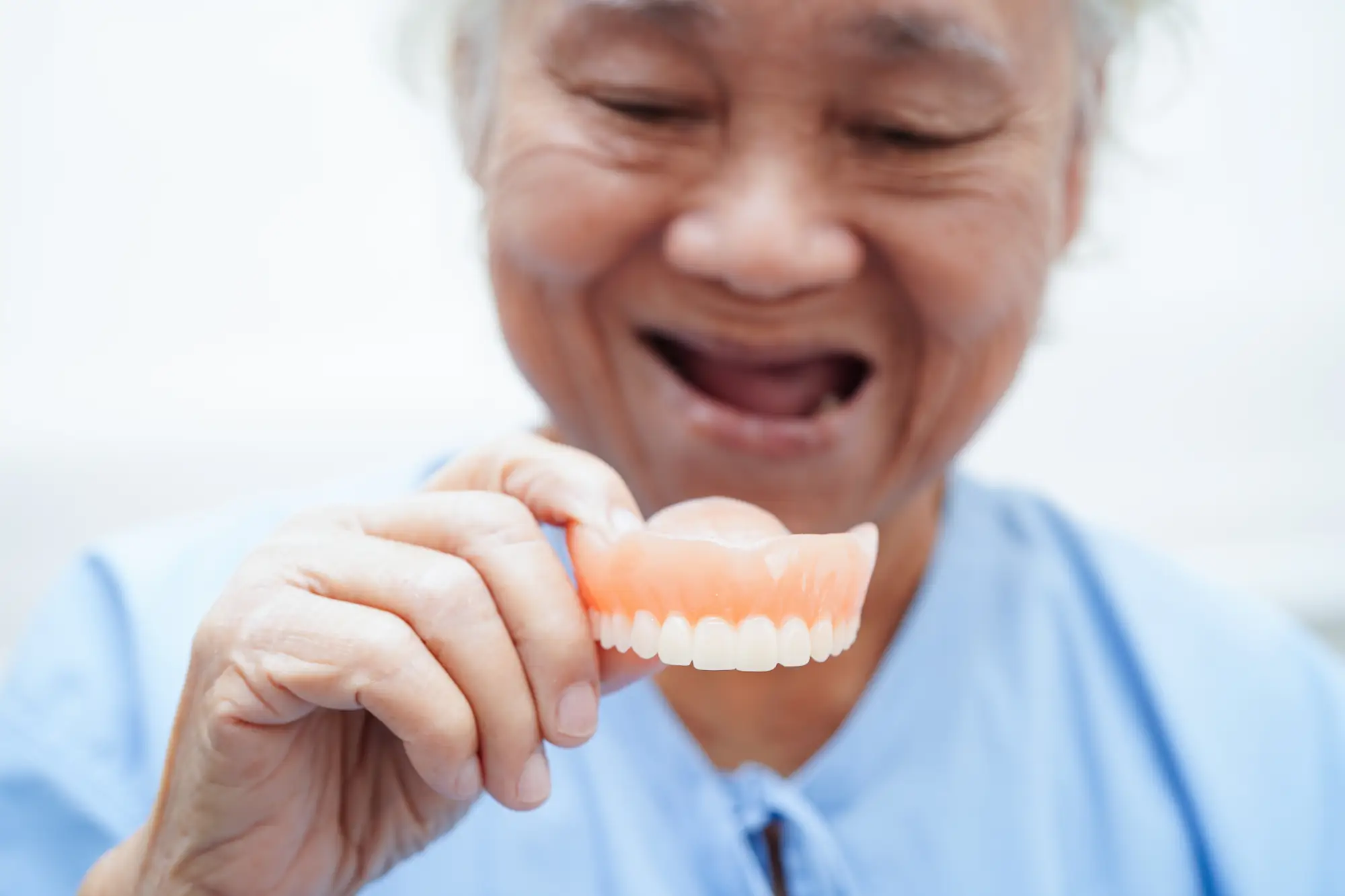 paciente-anciana-asiatica-con-protesis-dentales-en-la-mano-para-masticar-comida
