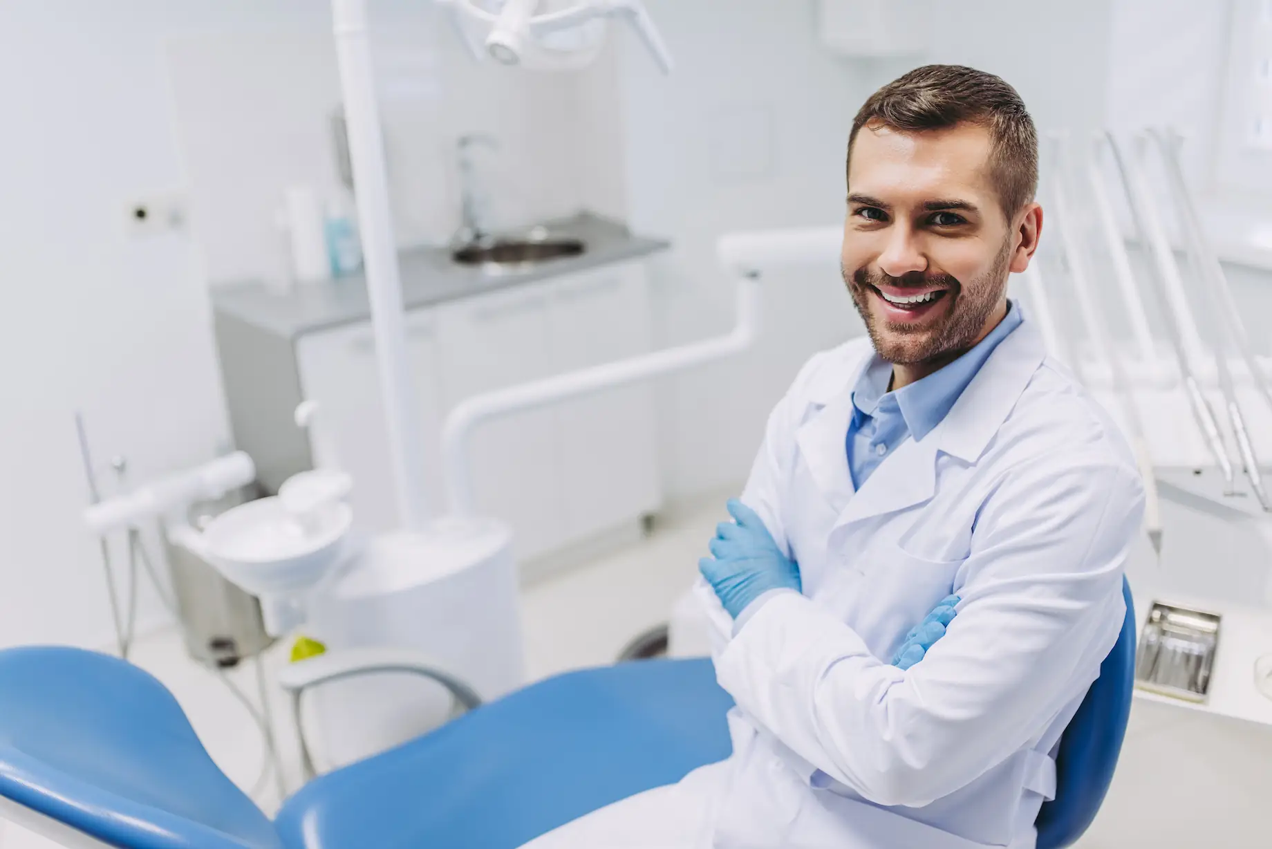 vista-aerea-de-un-medico-sonriente-con-las-manos-cruzadas-mirando-la-camara-en-la-clinica-dental